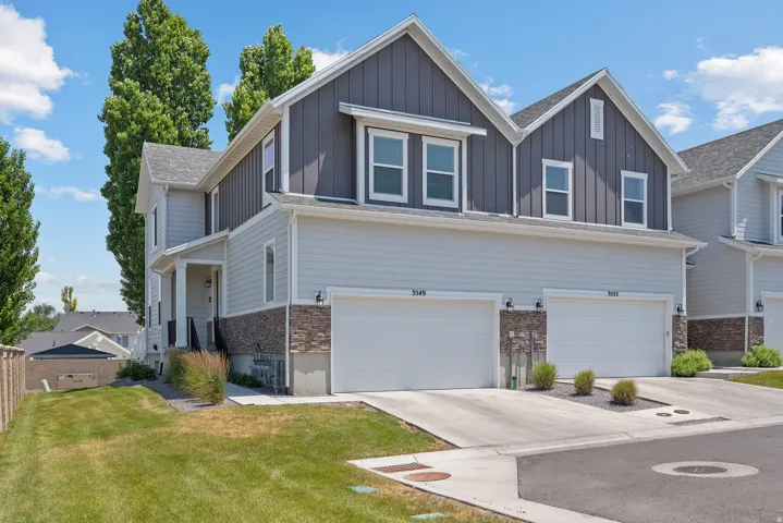 Contemporary townhouse exterior featuring light gray siding, dark gray vertical paneling, and stone accents