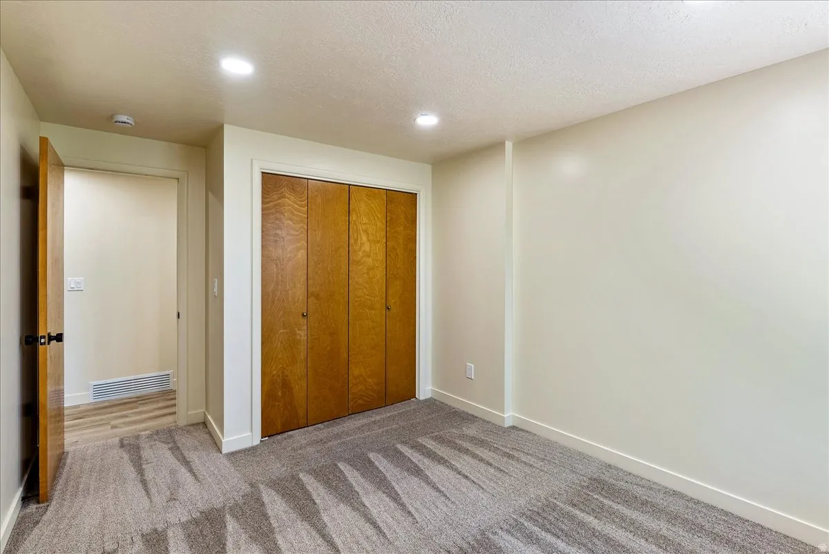Recessed lighting illuminates this room featuring wood-finish closet doors and light-toned walls