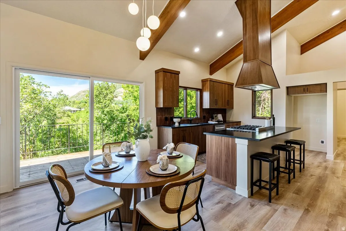 Open-concept living space with vaulted ceilings featuring exposed wood beams