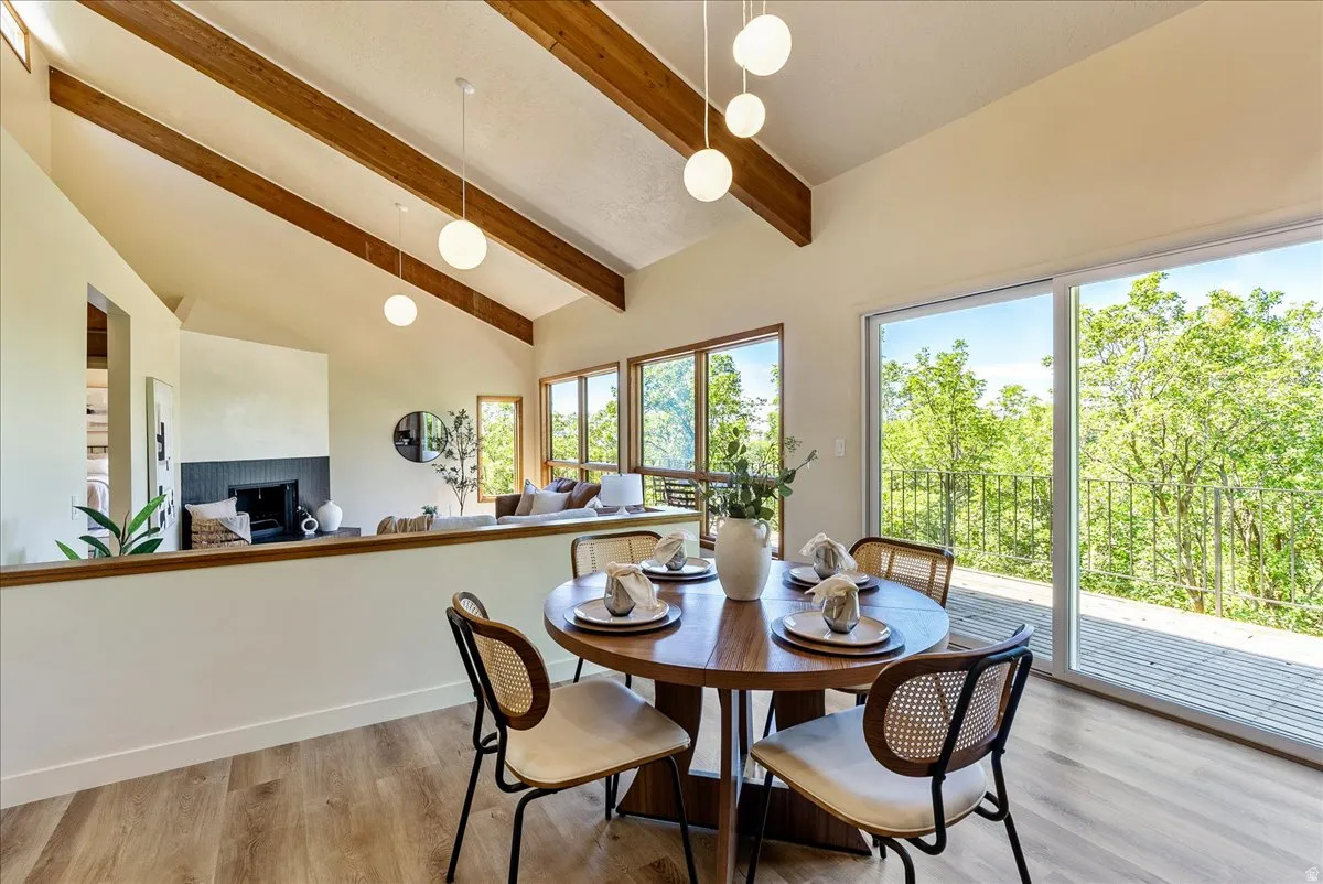 Dining area featuring a wood-finish flooring, vaulted ceiling with exposed wood beams, and contemporary pendant lighting
