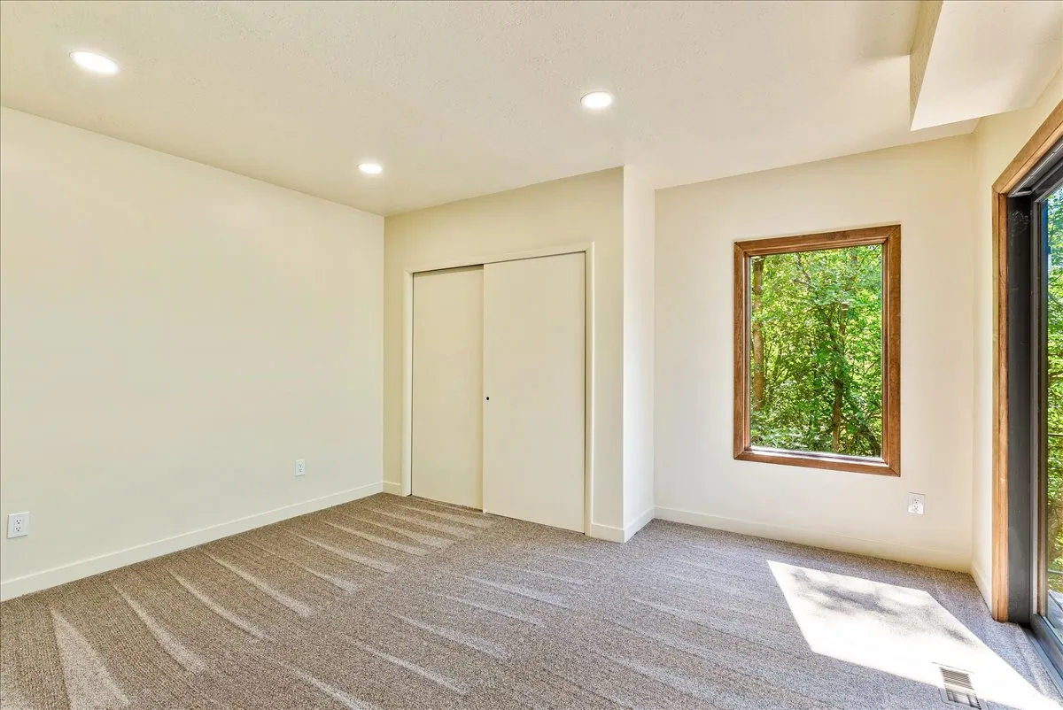 Neutral tone walls with recessed lighting and textured carpet flooring