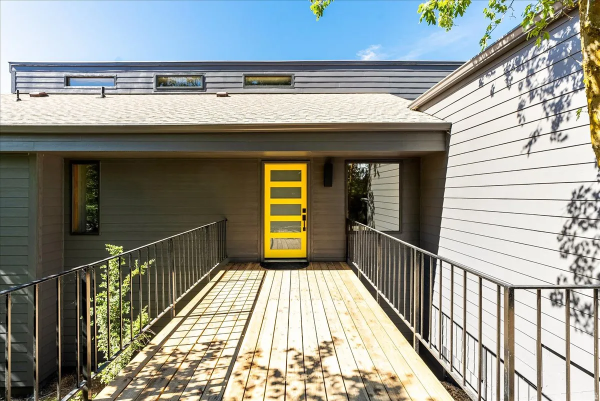 Modern exterior featuring a bright yellow entry door with horizontal glass panels