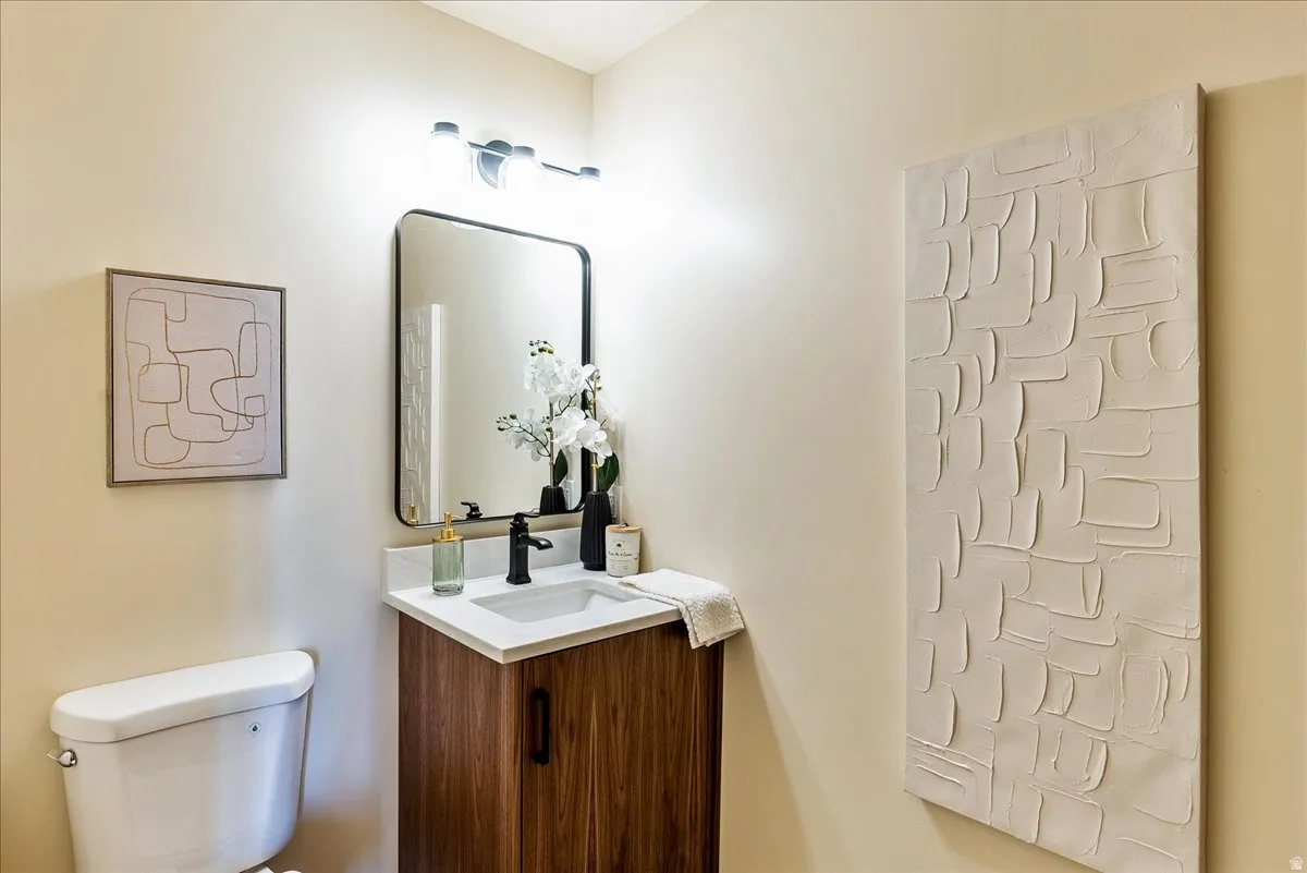 Bathroom featuring a wood-finish vanity with a white countertop and integrated sink, matte black faucet, and a black-framed mirror