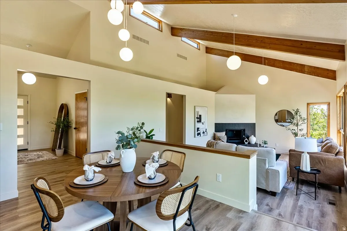 Open-concept living area with vaulted ceilings featuring exposed wood beams and abundant natural light from upper transom windows