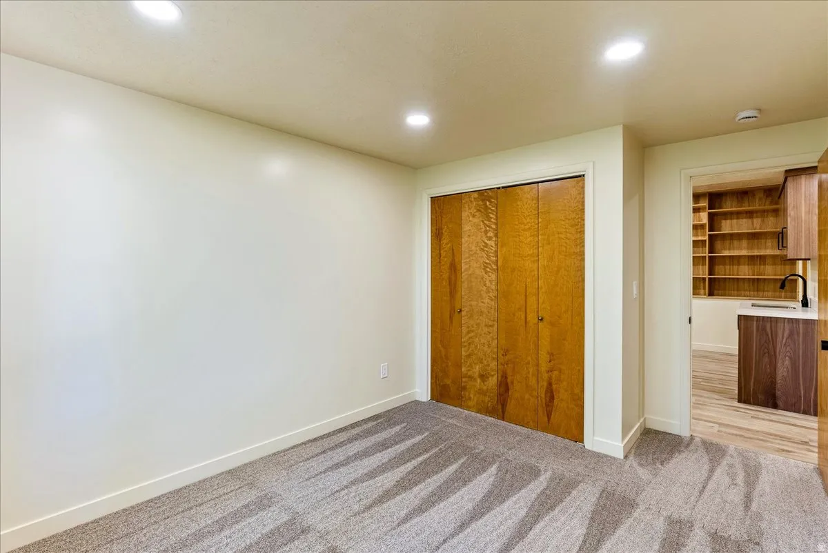 Recessed lighting illuminates a space featuring light-colored walls and patterned carpet