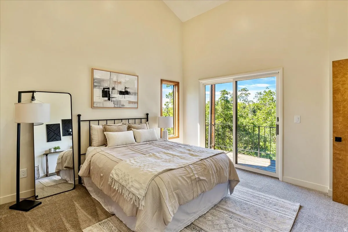 Light-filled room featuring vaulted ceilings and a glass sliding door leading to an outdoor balcony