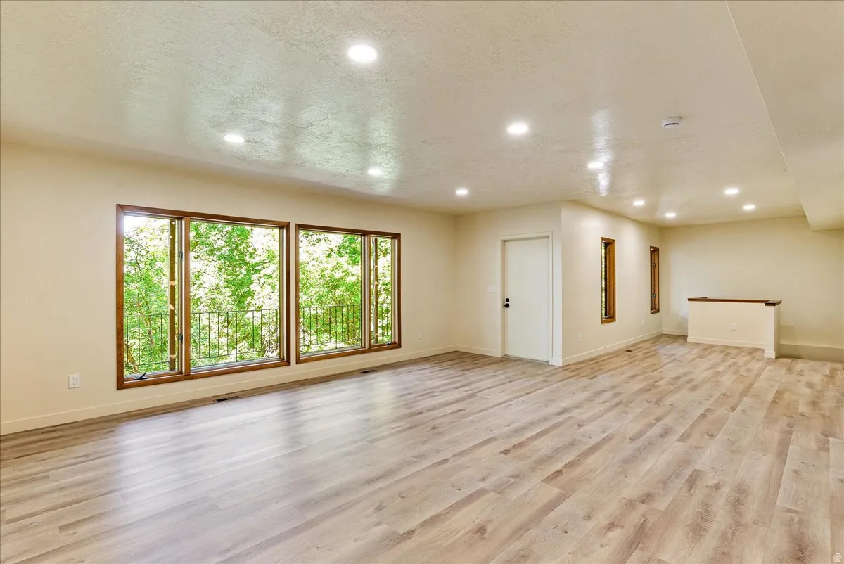 Expansive room featuring wood-finish flooring, recessed lighting, and large windows with dark wood frames