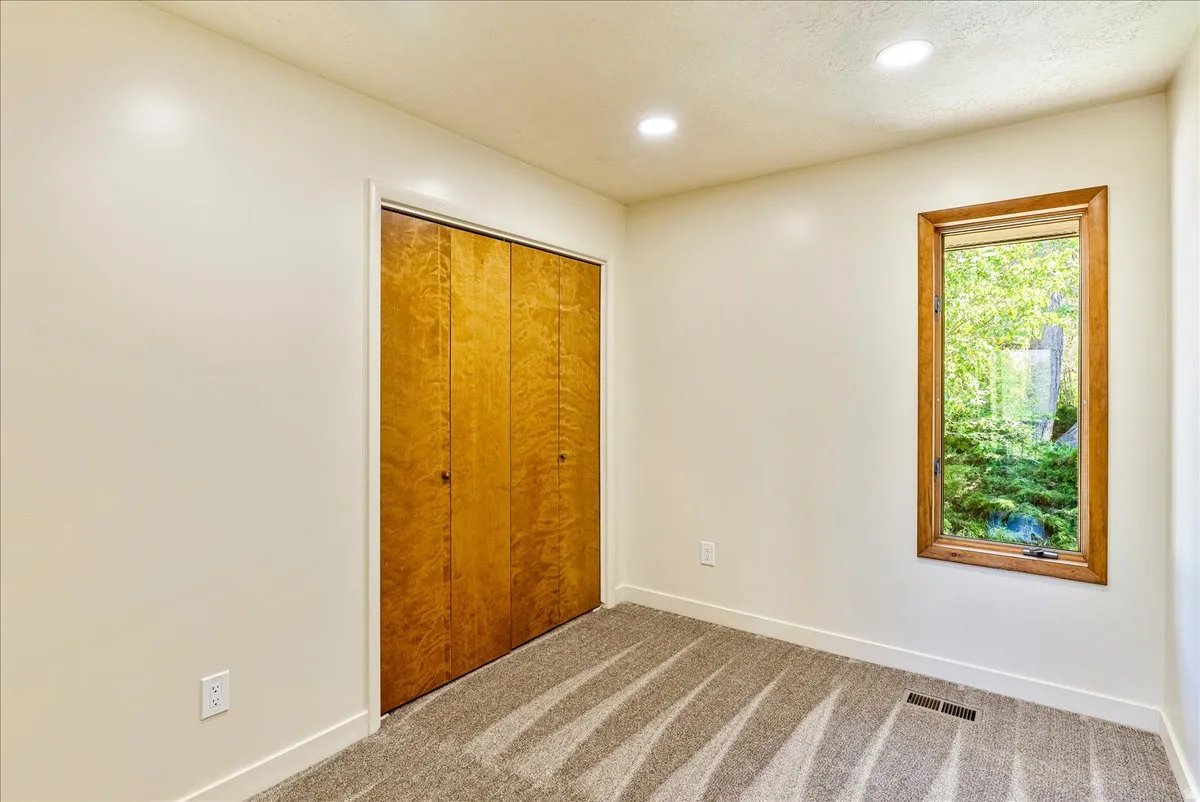Wood-finish bi-fold closet doors, recessed ceiling lighting, and a single window with wood framing