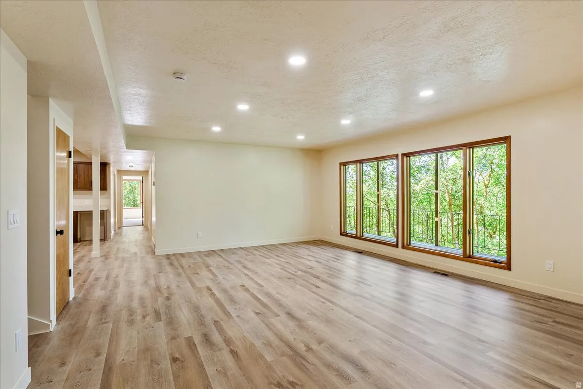 Spacious room featuring wood-finish flooring, recessed lighting, and large windows with wood trim