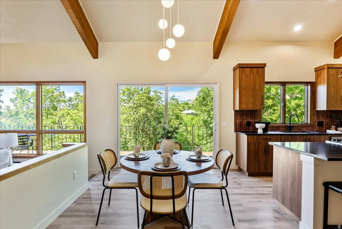 Vaulted ceilings with exposed wood beams, wood-finish flooring, and a modern spherical chandelier