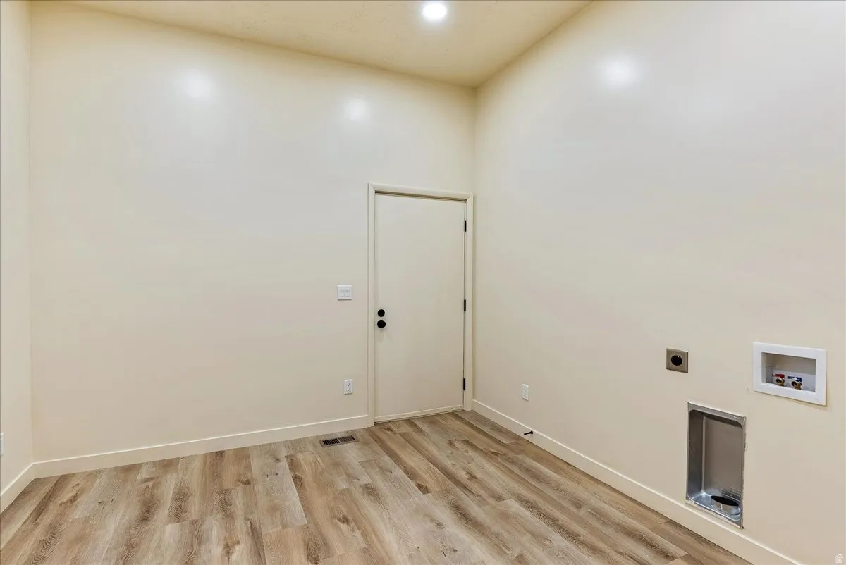 Dedicated laundry area featuring wood-finish flooring and light-toned walls
