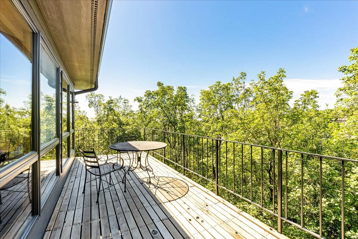 Expansive wood deck with black metal railings, offering tree-filled scenery