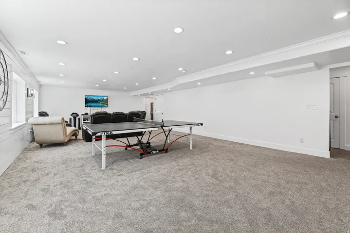 Spacious interior room featuring light gray carpeting, recessed ceiling lighting, and crown molding