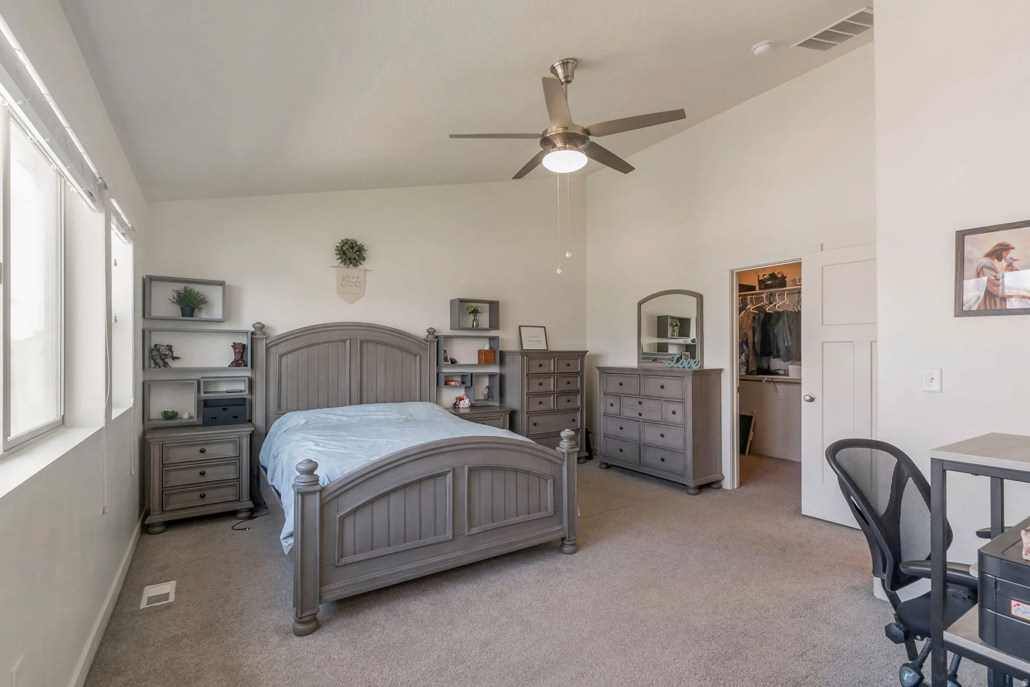 Carpeted room featuring multiple windows, a ceiling fan with integrated lighting, and a walk-in closet with a solid door