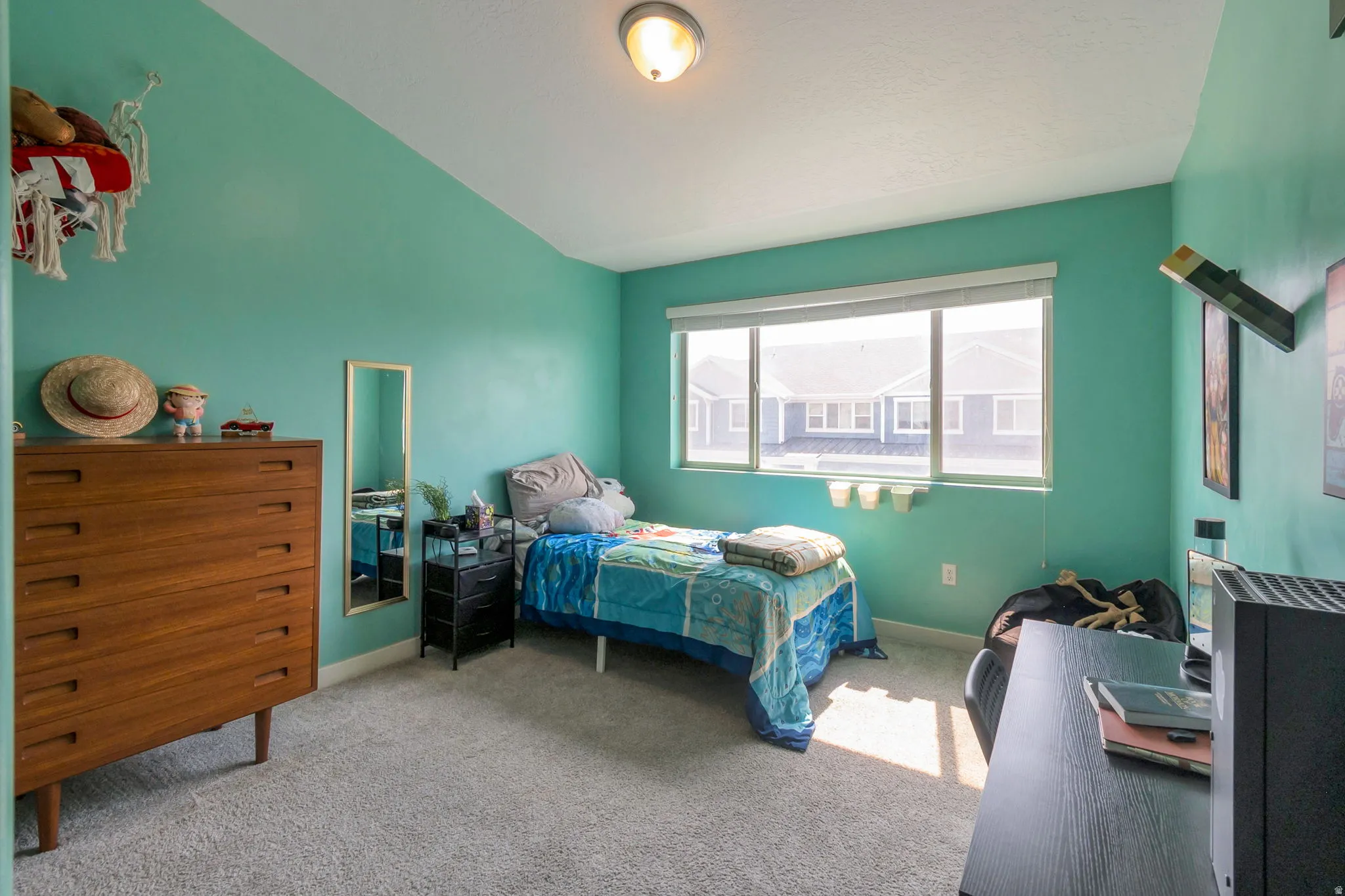 Bedroom featuring a large window with white blinds, light-toned carpet flooring, and a flush-mount ceiling light fixture