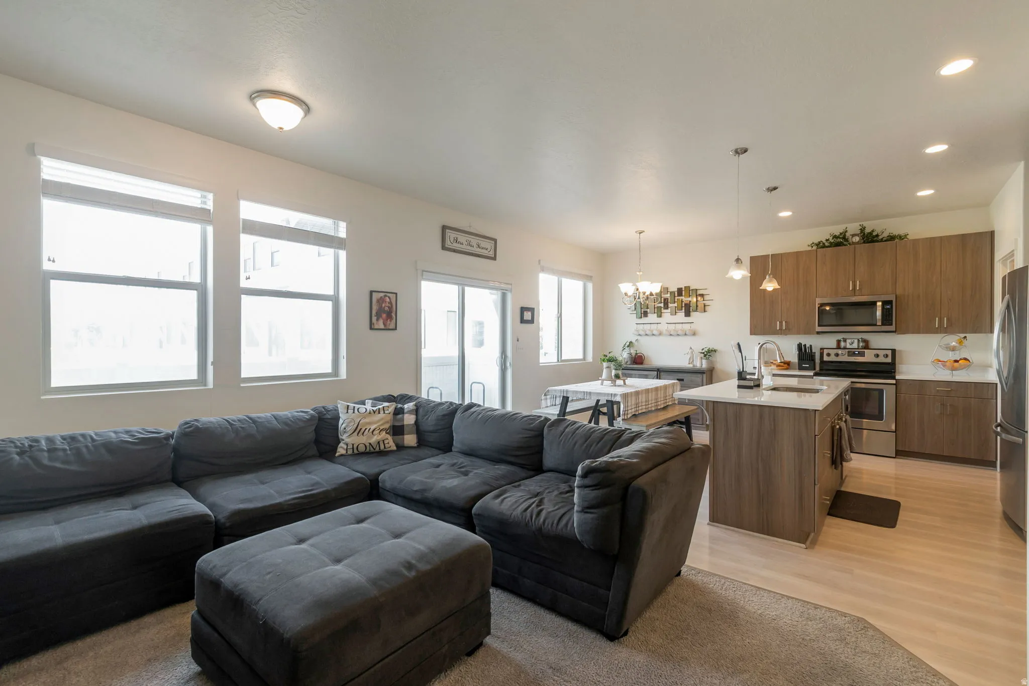 Open-concept living space featuring a kitchen island with seating, stainless steel appliances, wood-finish cabinetry, and recessed lighting
