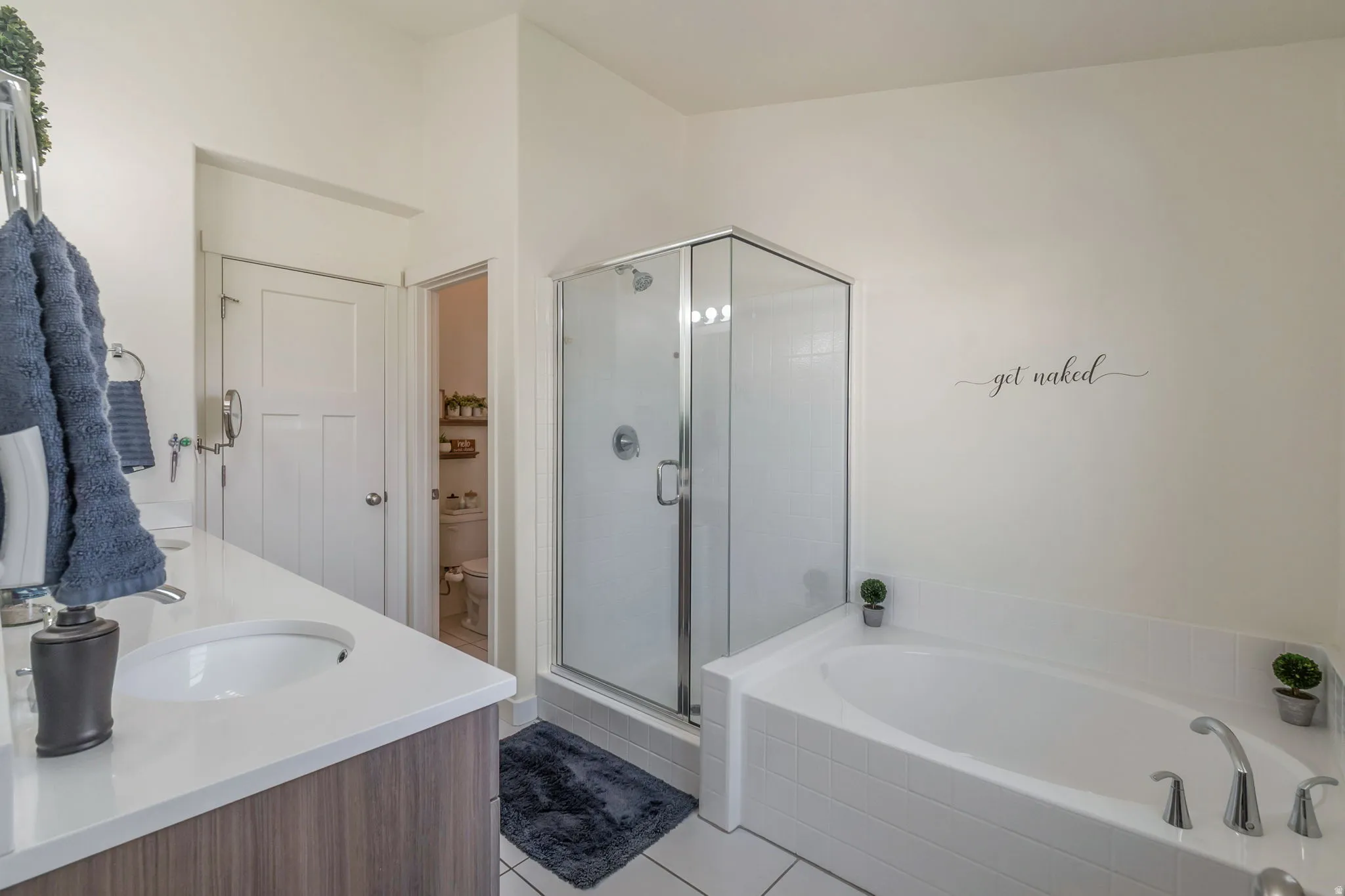 Bathroom featuring a built-in soaking tub, a clear glass shower enclosure, a vanity with a white countertop, and wood-finish cabinetry