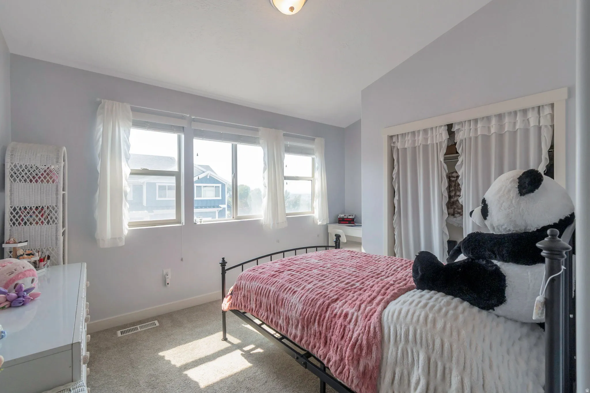 Bedroom featuring light gray walls, carpet flooring, a multi-pane window, and a closet with white curtains