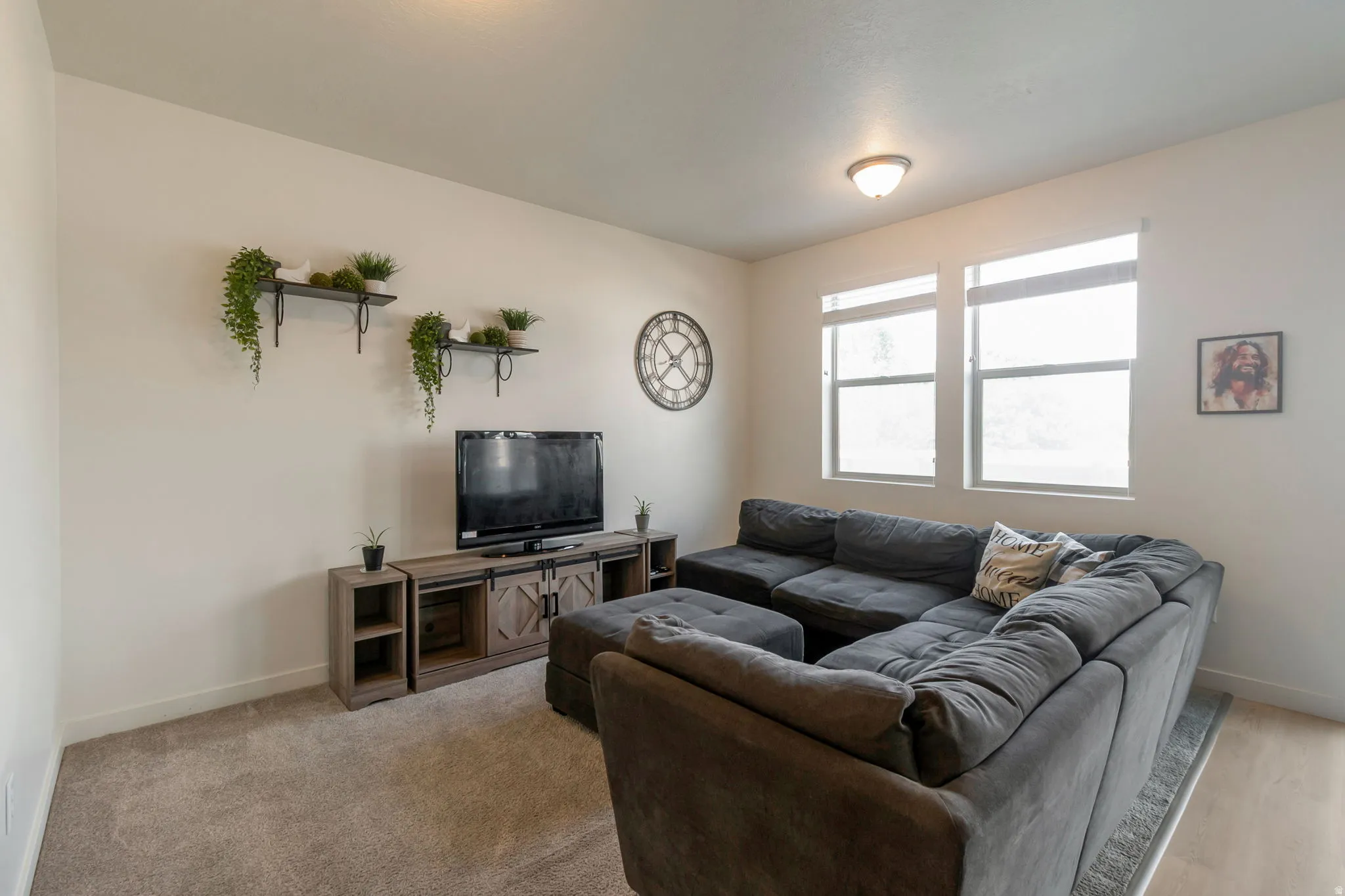 Living area featuring neutral wall paint, two bright windows, flush mount ceiling lighting, and soft carpet flooring