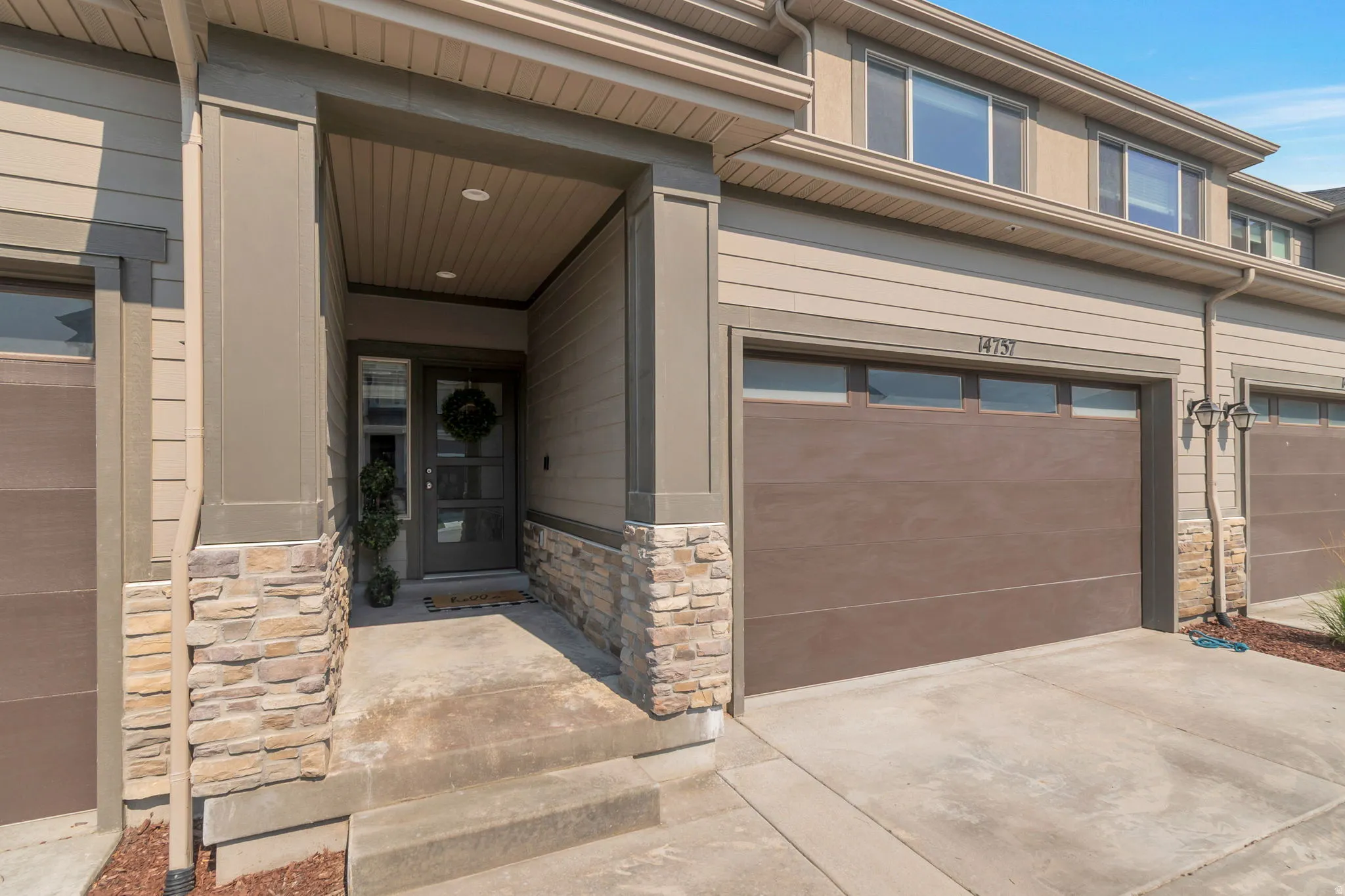 Entryway featuring a covered porch, a privacy glass door with vertical panels, and stone veneer accents