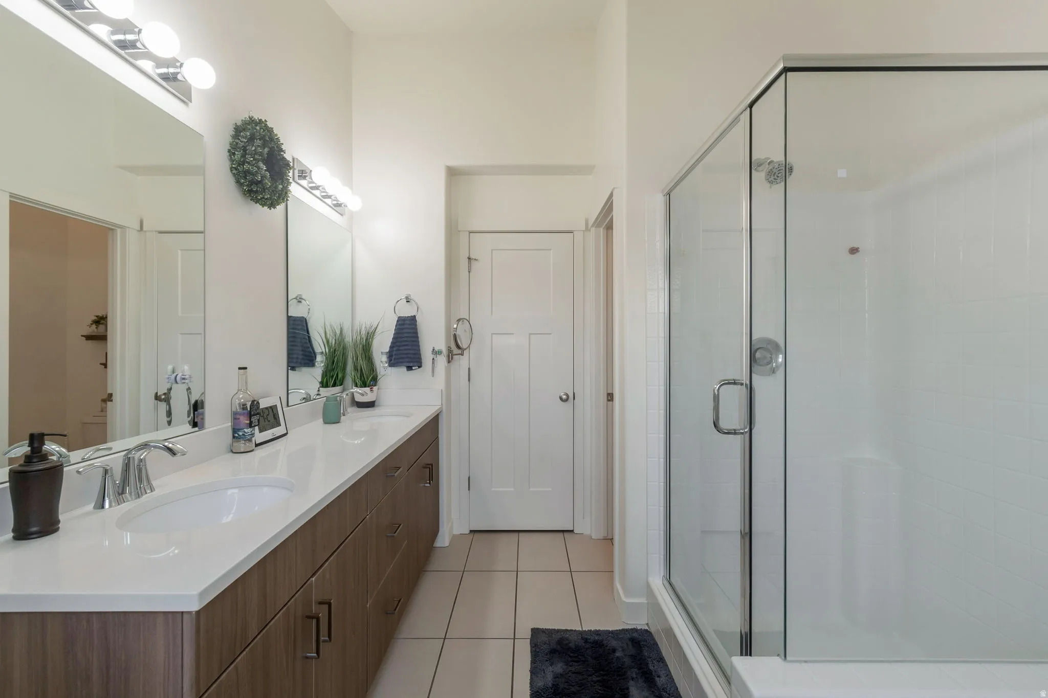 Bathroom featuring a dual vanity with a white countertop and wood-finish cabinetry, illuminated by overhead bar lighting