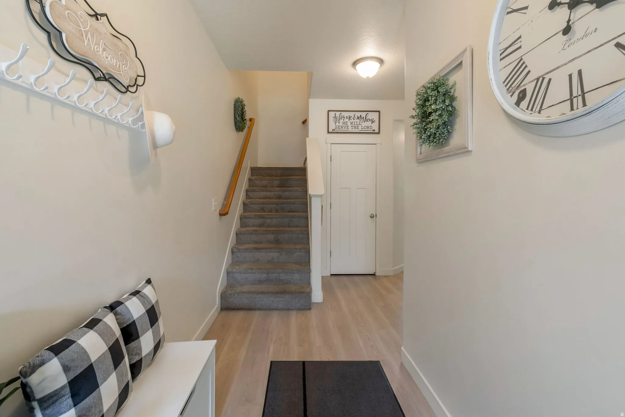 Entryway featuring light wood-finish flooring, a carpeted staircase with a wood handrail, and a white interior door