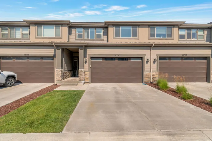 Multi-level townhome exterior featuring an integrated two-car garage and stone column accents