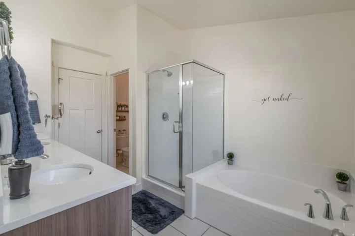 Bathroom featuring a built-in soaking tub, a clear glass shower enclosure, a vanity with a white countertop, and wood-finish cabinetry