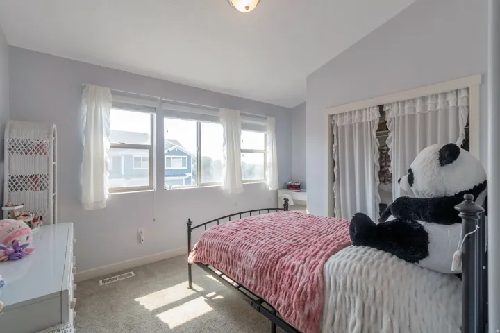 Bedroom featuring light gray walls, carpet flooring, a multi-pane window, and a closet with white curtains