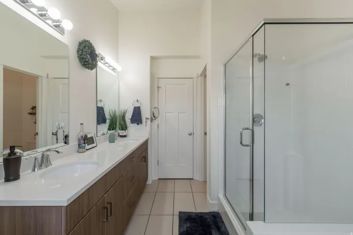 Bathroom featuring a dual vanity with a white countertop and wood-finish cabinetry, illuminated by overhead bar lighting