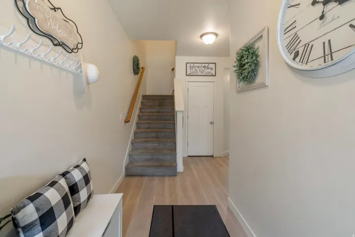 Entryway featuring light wood-finish flooring, a carpeted staircase with a wood handrail, and a white interior door