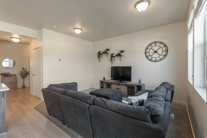 Open-concept living space featuring light wood-finish flooring, recessed ceiling lighting, abundant natural light from multiple windows, and a built-in media console with storage