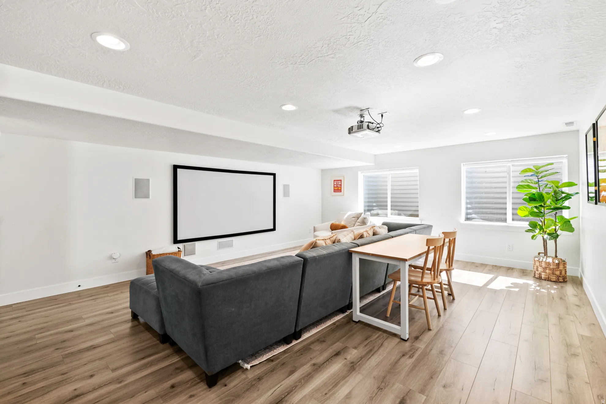 Entertainment room featuring a large projection screen, mounted projector, and recessed ceiling lighting