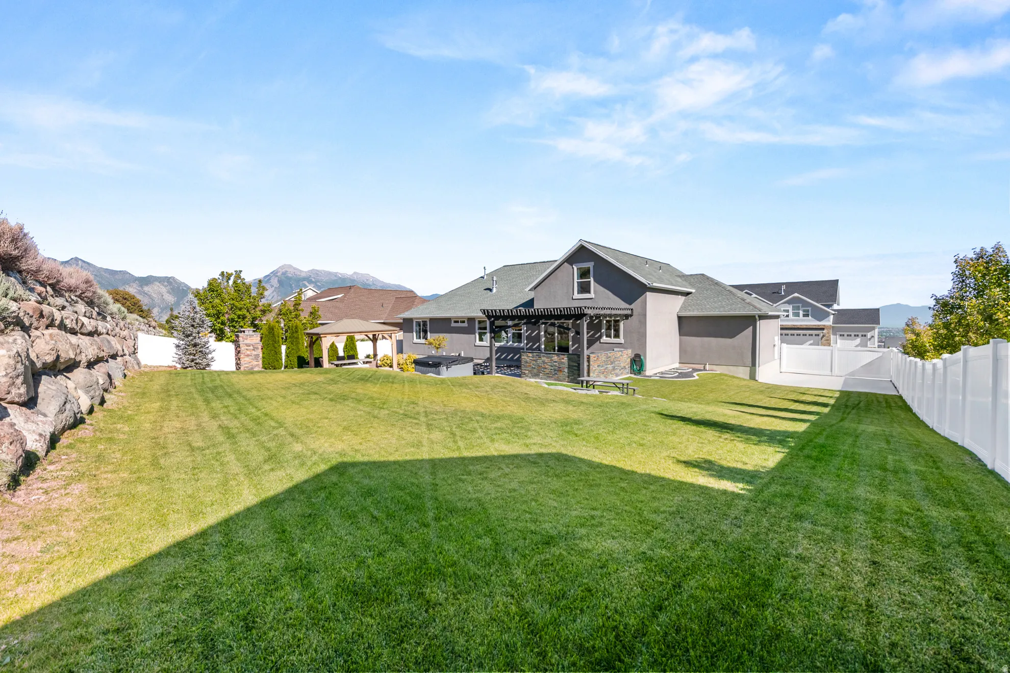Expansive green lawn with a white privacy fence