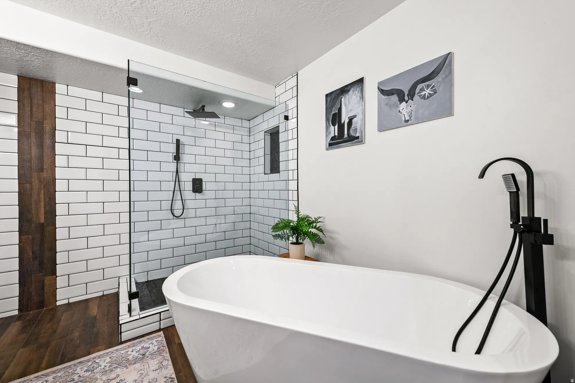 Freestanding soaking tub with a matte black floor-mounted faucet and hand shower