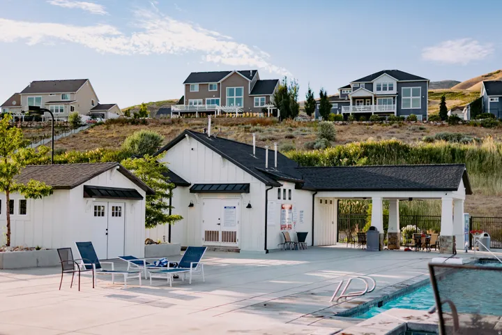 Community clubhouse featuring board and batten siding, dark shingle roofing, and a covered outdoor seating area