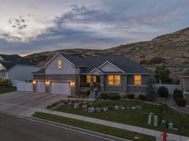 Stone and siding exterior with a multi-car garage, mature landscaping, and an elevated front entry