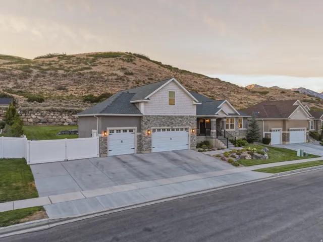 Stone and siding exterior with a multi-car driveway, attached garages, and a landscaped front yard