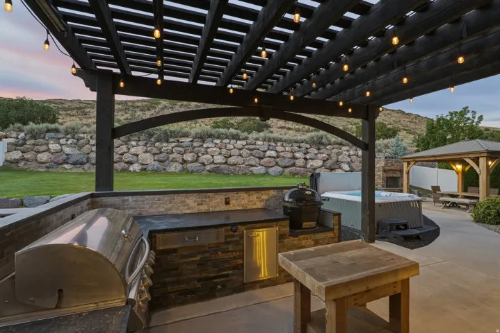 Outdoor kitchen featuring a built-in grill, integrated sink, and under-counter refrigerator