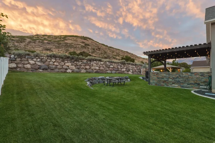 Expansive lawn area with a stone retaining wall and white fencing