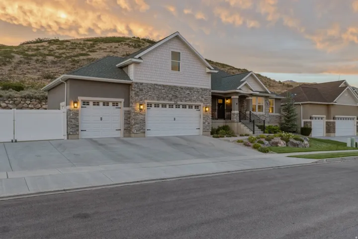 Stone and siding exterior with a multi-car driveway and an attached garage