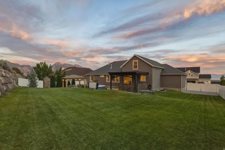 Expansive green lawn with a white privacy fence and a stone retaining wall