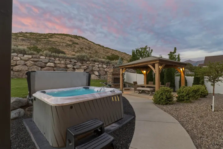 Hot tub, stone retaining wall, paved walkway, open-air gazebo, and built-in fireplace