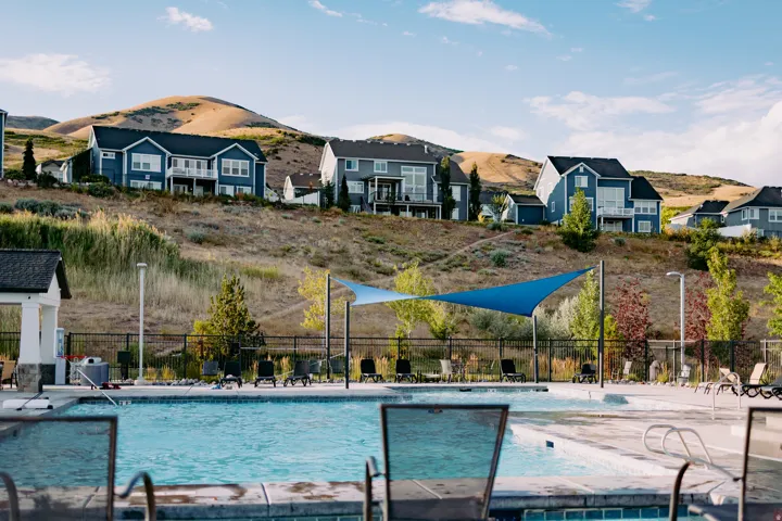 Resort-style swimming pool featuring a shaded lounge area, surrounding concrete decking, and a distant mountain backdrop