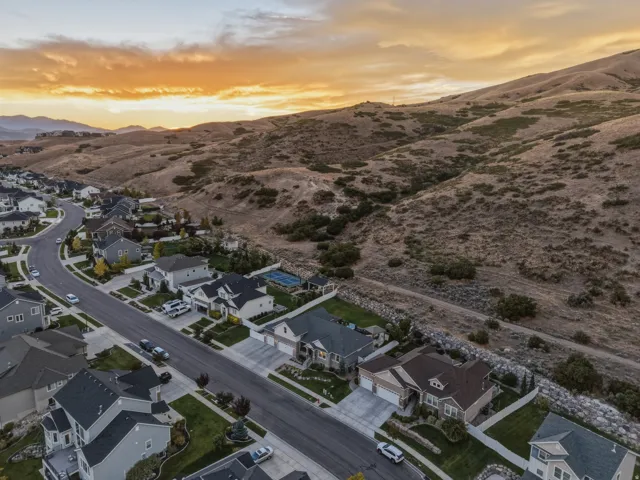 Residential neighborhood with a winding street, established homes, landscaped yards, and mountain backdrop