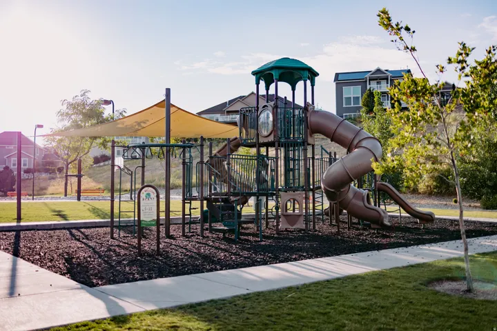 Community playground featuring a multi-level play structure with tube slides, open slides, and climbing elements
