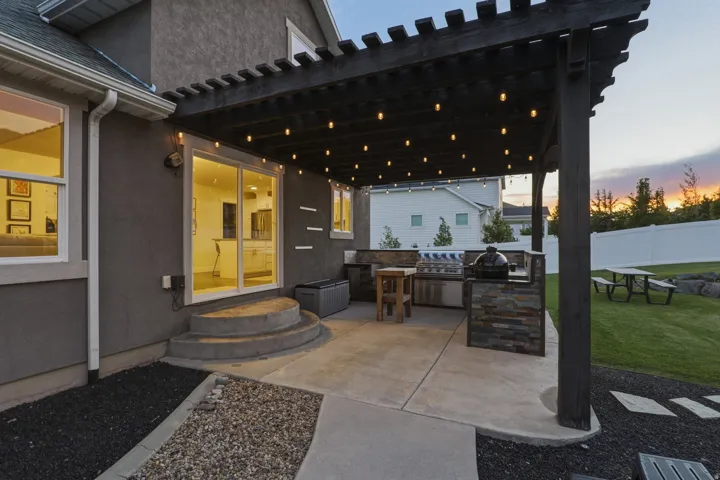 Outdoor living space featuring a dark wood pergola, string lighting, and an integrated outdoor kitchen