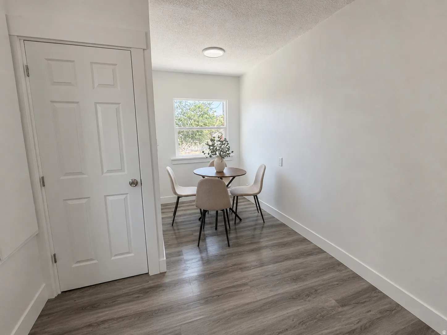 Bright interior space featuring wood-finish flooring, white walls, and a window for natural light