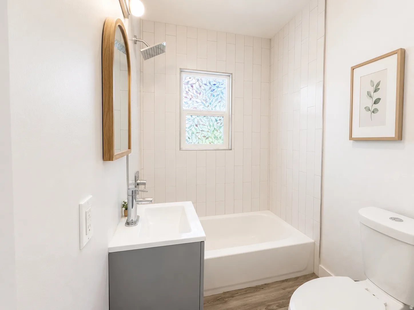 Bathroom featuring a white subway tile shower surround, showerhead with extended arm, and a window with decorative privacy film