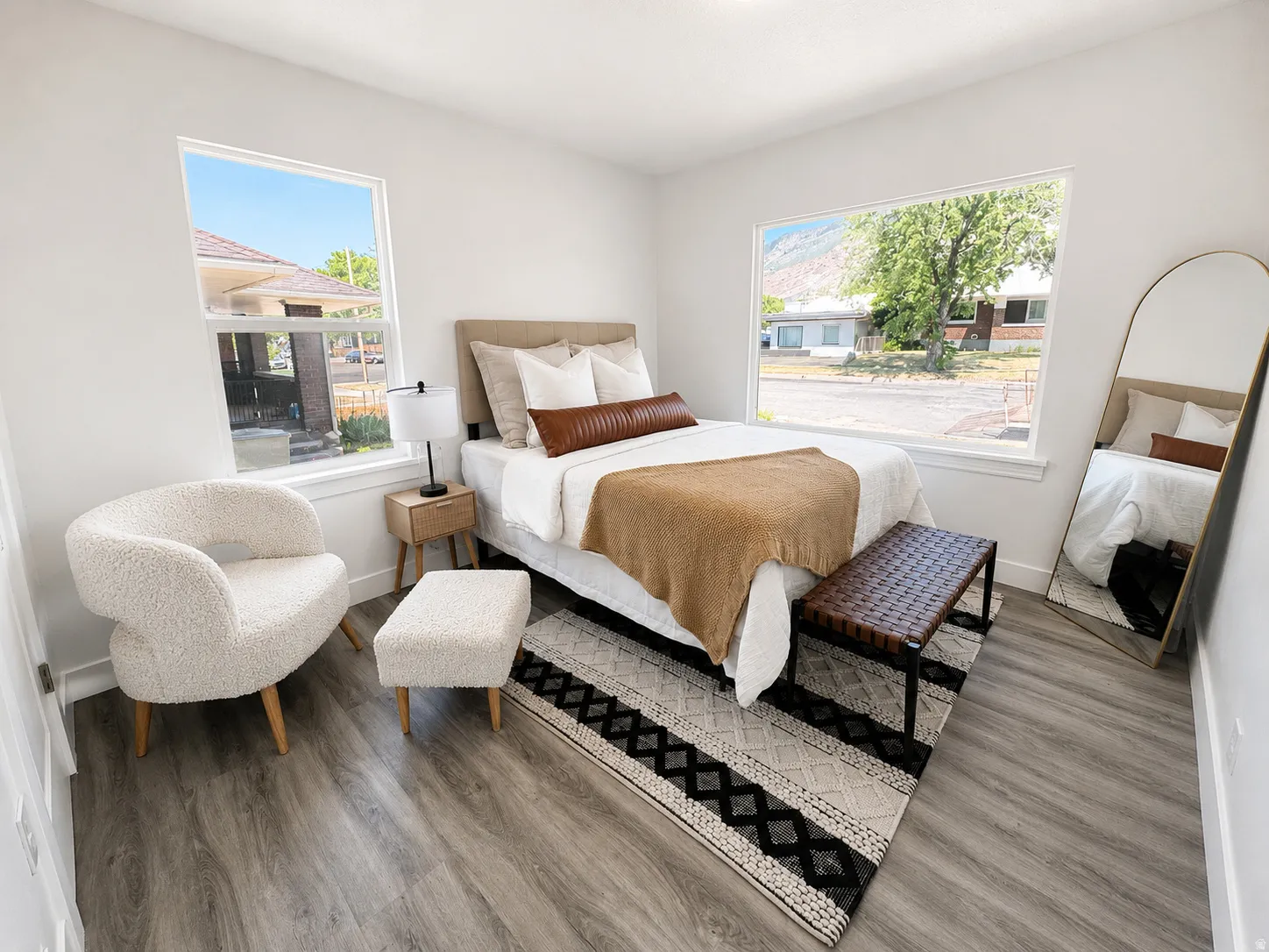 Spacious room featuring wood-finish flooring, two large windows, and bright white walls